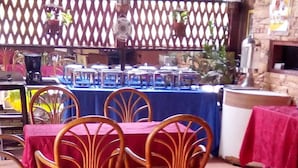Restaurante com mesas cobertas por toalhas vermelhas e cadeiras de vime.