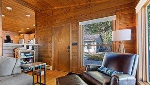 L’intérieur d’un chalet accueillant, avec un canapé en cuir, une petite table et une bibliothèque.