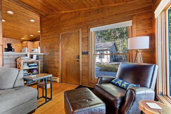 L’intérieur d’un chalet accueillant, avec un canapé en cuir, une petite table et une bibliothèque.