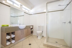 Ein modernes Badezimmer mit Duschkabine aus Glas, einem weißen Waschbecken und einer Toilette.