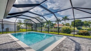 A covered outdoor swimming pool with a clear view of the surrounding neighborhood. - Cozy in the Cape, Heated Saltwater Pool & Gulf access, water view  (Cape Coral)