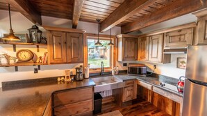 A kitchen with wooden cabinets, a stainless steel refrigerator, a microwave, and a sink. - Max's Cabin at Tiny Timbers Resort and Spa! (South Fork)