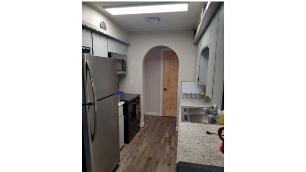 Una cocina compacta equipada con refrigerador, horno, microondas y lavamanos.