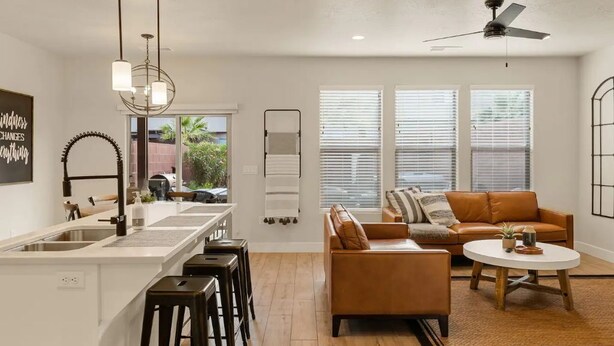 Una cocina moderna con una isla central, taburetes de bar y un comedor con una mesa redonda.