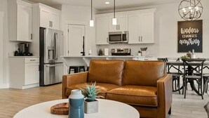 Una cocina moderna con armarios blancos, electrodomésticos de acero inoxidable e iluminación colgante.