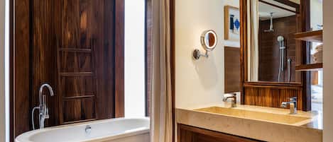 Un baño con una bañera independiente, un tocador con espejo y una zona de ducha.