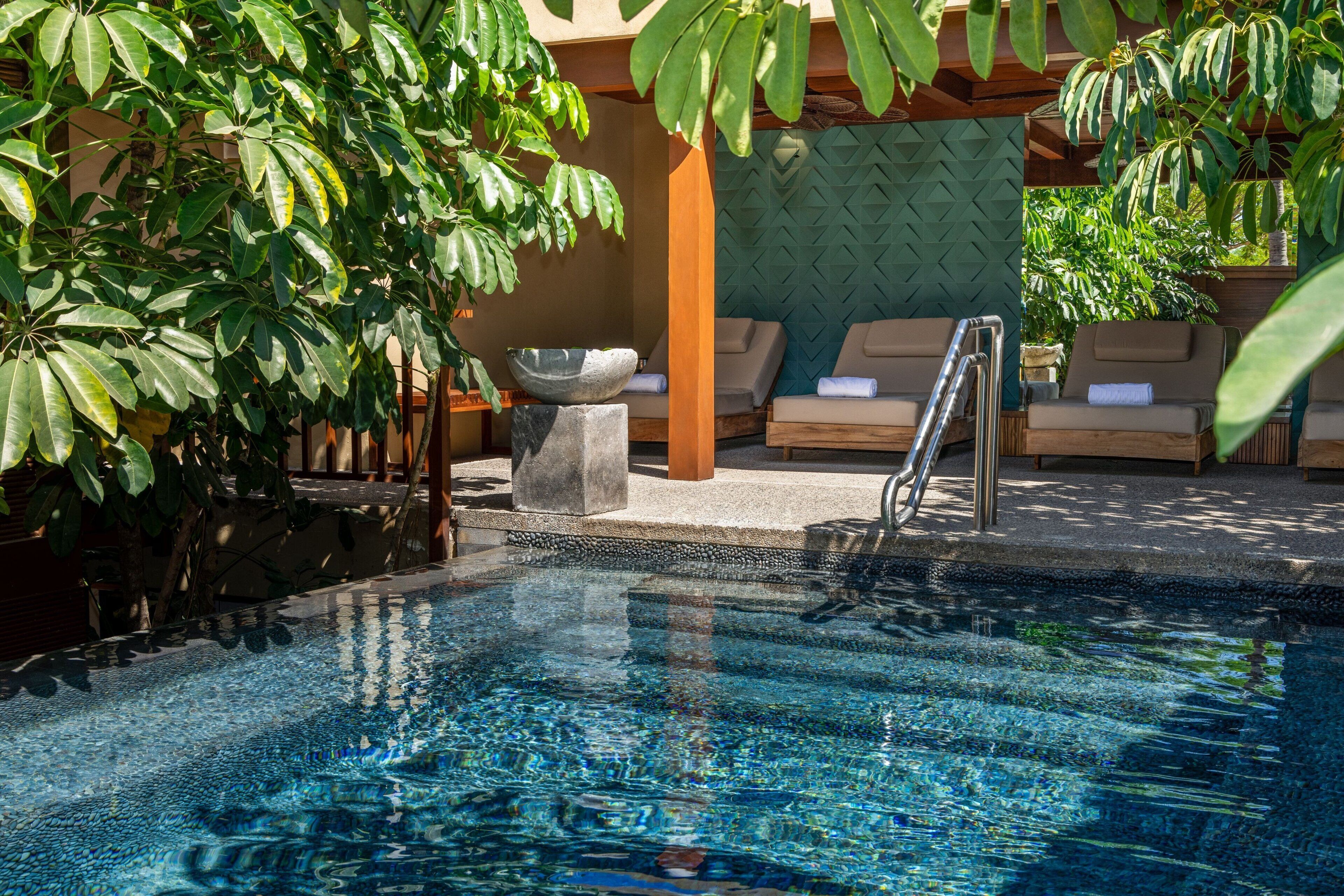Un área de piscina con sillas de descanso y una pila de piedra.