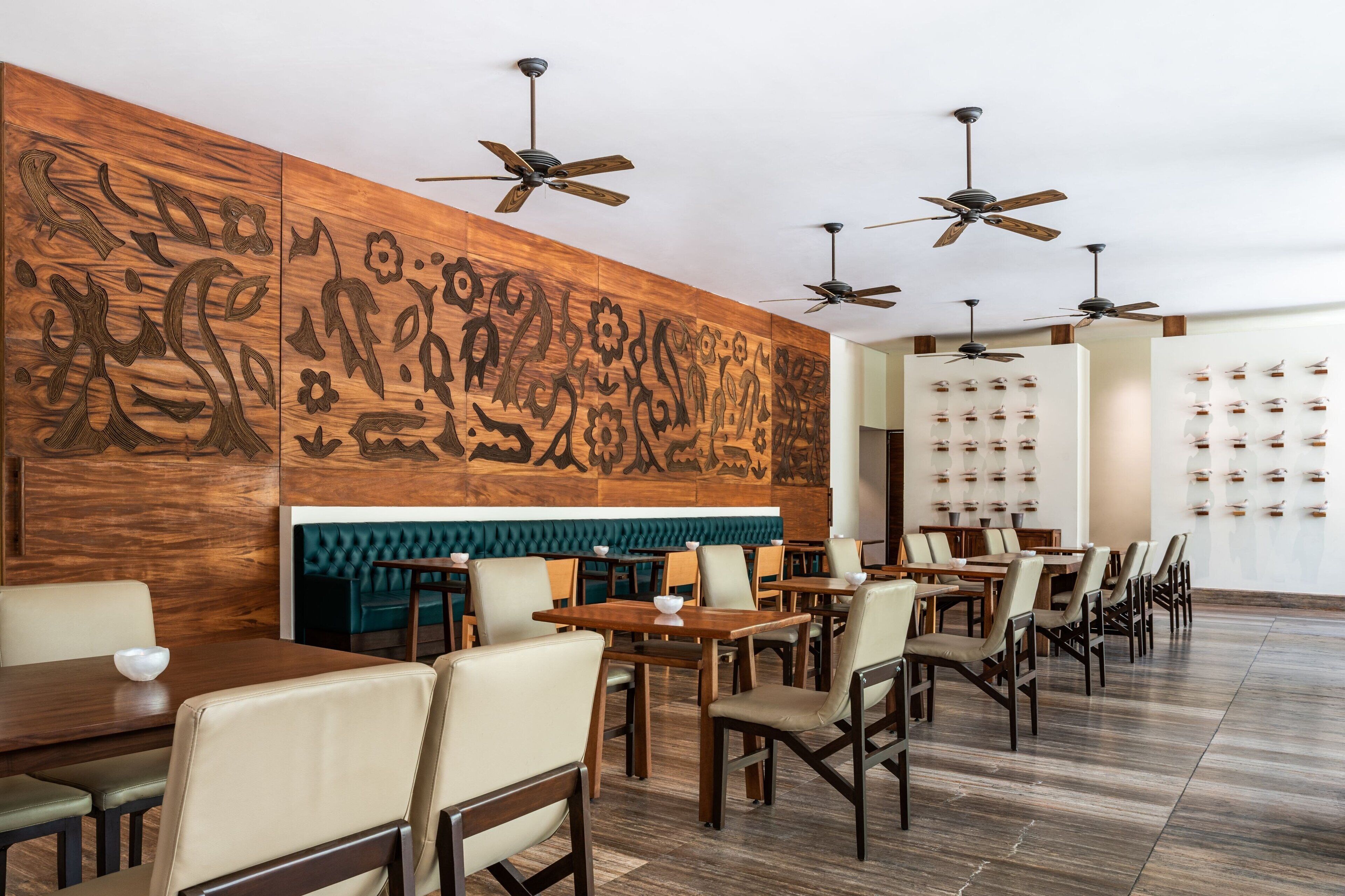 A restaurant with wooden panel walls, ceiling fans, and a row of tables and chairs.