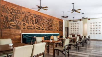 A restaurant with wooden panel walls, ceiling fans, and a row of tables and chairs.