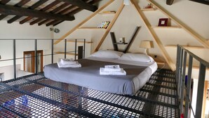 A bedroom with a bed, wooden beams, a ladder, and a shelf with items. - Abode of the Acetari in Campo de 'Fiori (Roma)