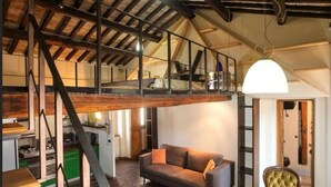 A loft-style room with a wooden ceiling, a dining table, a sofa, and a kitchen area. - Abode of the Acetari in Campo de 'Fiori (Roma)