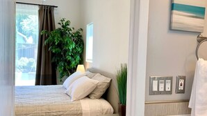 A bedroom with a bed, a bedside table, a potted plant, and a view of the outdoors. - Newly remodeled spacious 2bed/2bath with backyard in Willow Glen (San Jose)