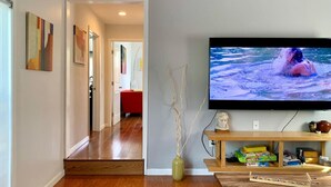A living room with a flat-screen TV mounted on the wall, a wooden coffee table, and a bookshelf with various items. - Newly remodeled spacious 2bed/2bath with backyard in Willow Glen (San Jose)