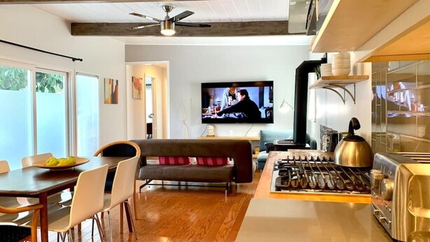A modern kitchen with a gas stove, a toaster, and a kettle. There is a dining area with a table and chairs, and a living room with a sofa and a television. - Newly remodeled spacious 2bed/2bath with backyard in Willow Glen (San Jose)