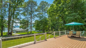 A wooden deck with outdoor furniture, a view of a lake, and a house in the background. - The Tiger Lily - A PMI Scenic City Vacation Rental (Whitwell)