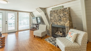 A living room with a stone fireplace, wooden flooring, and a TV. - The Tiger Lily - A PMI Scenic City Vacation Rental (Whitwell)