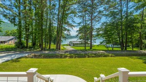 A view of a lakeside property with a grassy lawn, a wooden deck, and a house in the background. - The Tiger Lily - A PMI Scenic City Vacation Rental (Whitwell)