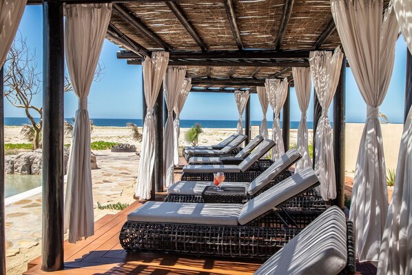 A beachside lounge area with cushioned seating and a view of the ocean.