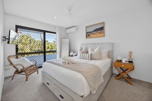 Een slaapkamer met een bed, een stoel, een nachtkastje, een afbeelding en uitzicht op het landschap.
