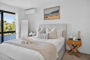 A bedroom with a bed, a nightstand, a mirror, and a beach view. - The River View - 10 min walk to Noosa Beach (Noosa Heads)