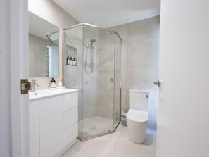 A modern bathroom with a glass-enclosed shower, a white sink, and a toilet. - Family First Floor Apt - 800m to Hastings Street! (Noosa Heads)