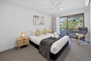 A bedroom with a bed, bedside table, chair, and a large window with a view. - Noosa Parade Escape - 800m to Hastings Street! (Noosa Heads)