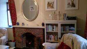 Una sala de estar acogedora con chimenea de ladrillo, una estantería y un espejo en la pared.