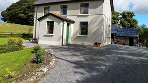 Una casa de dos pisos con techo inclinado, una puerta verde y un pequeño porche.