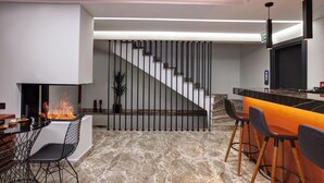 A modern kitchen with a built-in fireplace, a bar area with stools, and a staircase leading to an upper level. - Xenia Hotel Istanbul (Istanbul)