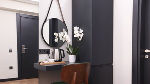 A modern kitchen with a wooden chair, a round mirror, and white orchids on the counter. - Xenia Hotel Istanbul (Istanbul)
