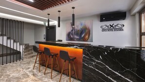 A modern hotel reception area with a marble reception desk, bar stools, and a contemporary art piece. - Xenia Hotel Istanbul (Istanbul)