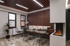 A modern interior with a wooden slatted wall, a round table with chairs, a sofa, and a fireplace. - Xenia Hotel Istanbul (Istanbul)