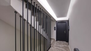 A hallway with a marble floor, a black door, and a staircase with black balusters. - Xenia Hotel Istanbul (Istanbul)
