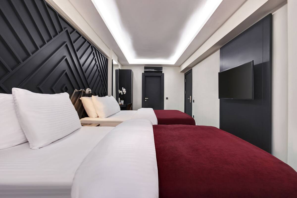 A hotel room with two beds, a TV, and a modern design.