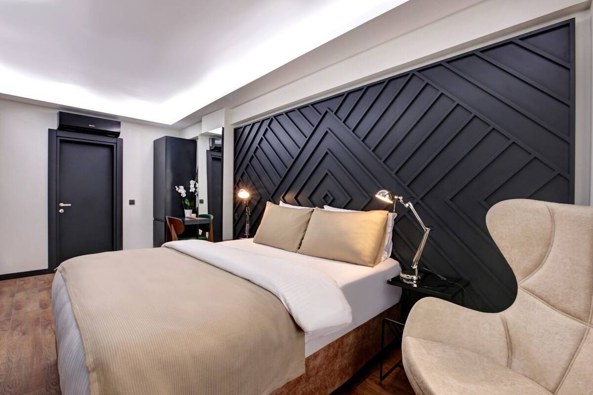 A modern bedroom with a large bed, a desk, and a chair.