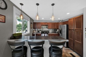 Enjoy cooking in this well-equipped kitchen with a large island, stainless steel appliances, and pendant lighting.