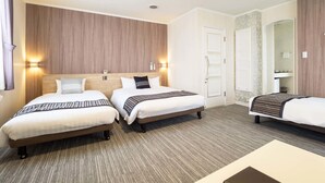 Habitación de hotel con dos camas, un espejo grande y un baño visible a través de una puerta abierta.