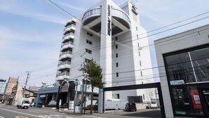 Un hotel moderno con fachada curva, varios balcones y una entrada espaciosa.