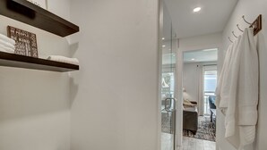 Casa de banho com sanita, barra para toalhas e prateleira com toalhas.