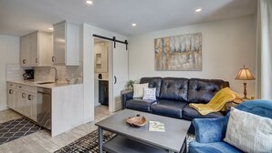 Uma sala de estar moderna com sofá, mesa de centro e área de cozinha com armários e pia.