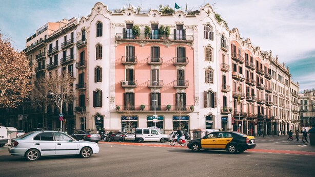 A street view with a row of buildings, a cyclist, and cars. - Anakena House (Barcelona)