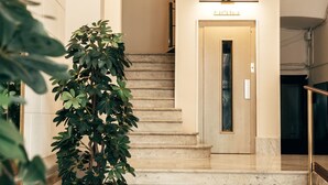 A marble staircase leading to a door with a sign reading "PLANETASA". - Anakena House (Barcelona)