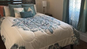 Une chambre à coucher avec un grand lit, deux tables de chevet et une petite table d’appoint.