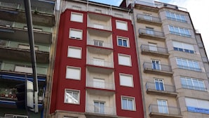 A multi-story building with balconies, a ground-floor café and bar, and a visible business sign. - Hotel Mino (Ourense)