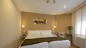 A double bed with white linens, a bedside table with a lamp, a chair, and a wall-mounted artwork. - Hotel Mino (Ourense)