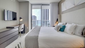 Une chambre d’hôtel moderne avec un grand lit, un bureau et une télévision.