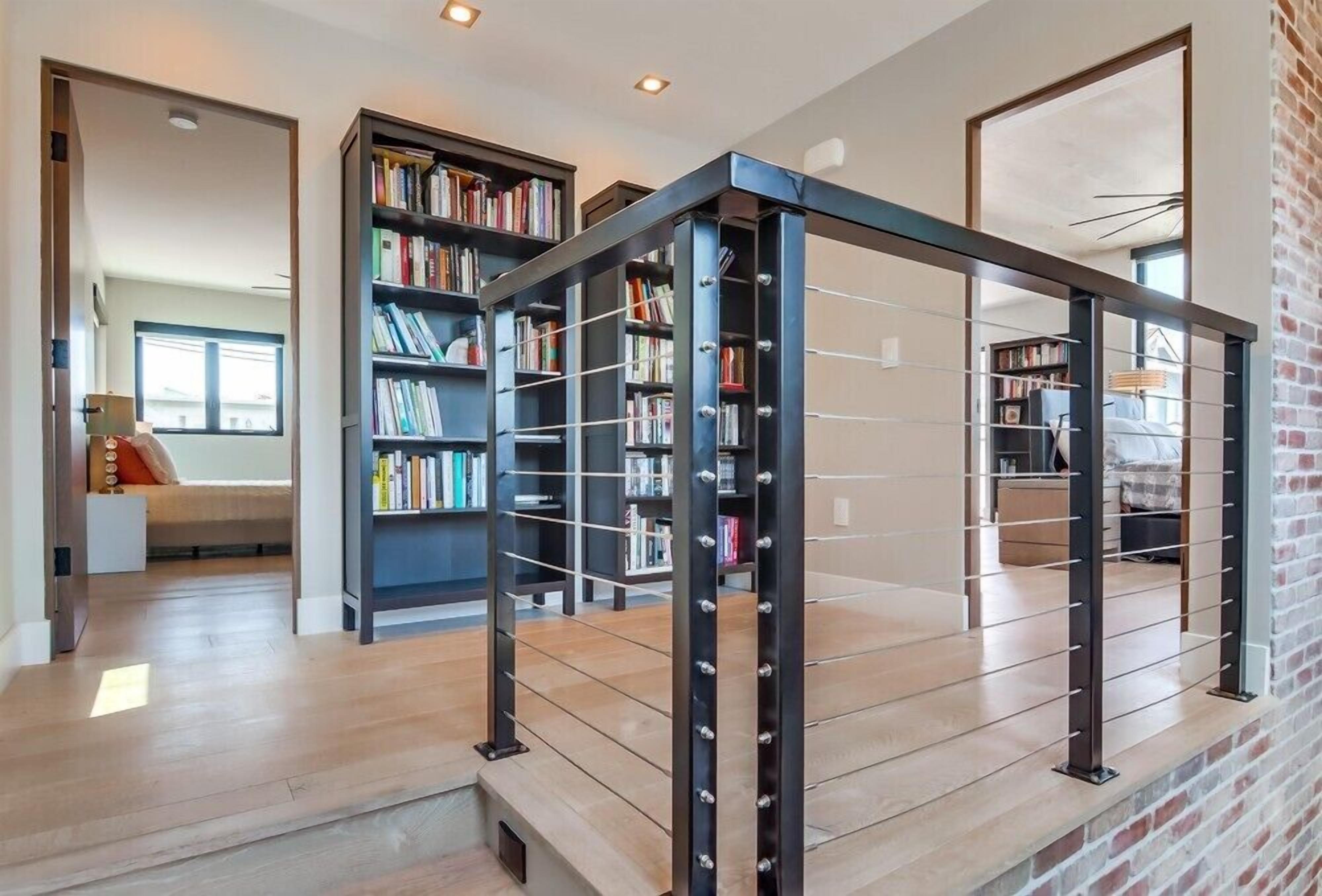 A modern interior with a staircase, bookshelves, and a brick wall.
