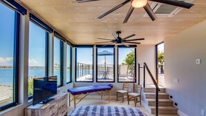 A bedroom with a large window, a ceiling fan, a bed, and a view of the water. - Modern WaterFront House * 2 Levels * 4 Parking * AC (San Diego)