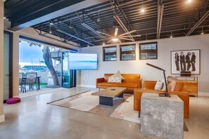 A modern living room with a large TV, two sofas, a coffee table, and a ceiling fan.