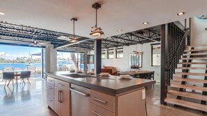 A modern kitchen with a large island, pendant lights, and a view of the ocean. - Modern WaterFront House * 2 Levels * 4 Parking * AC (San Diego)